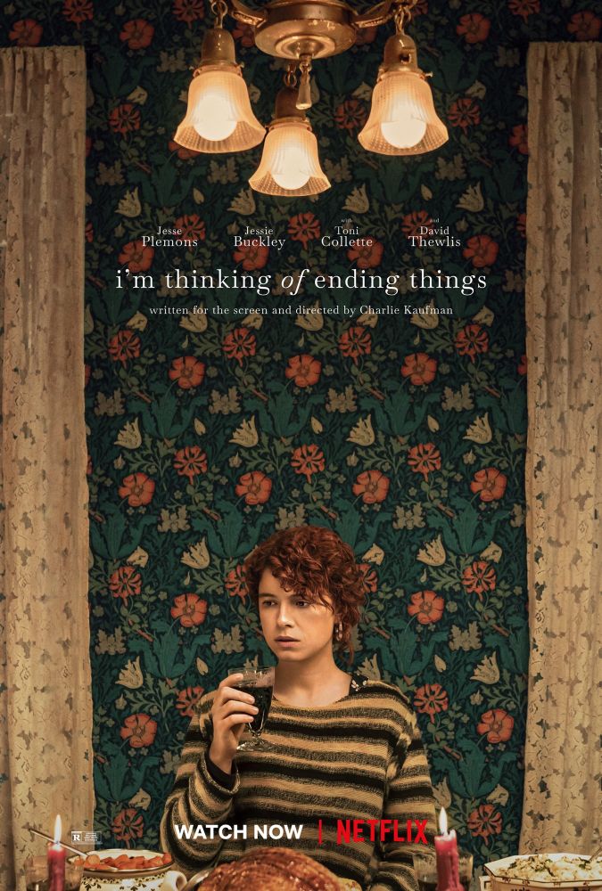 Movie poster for I’m Thinking of Ending Things. A girl sits at a table with ham, carrots, and mashed potatoes surrounding her with a glass on wine in hand. 