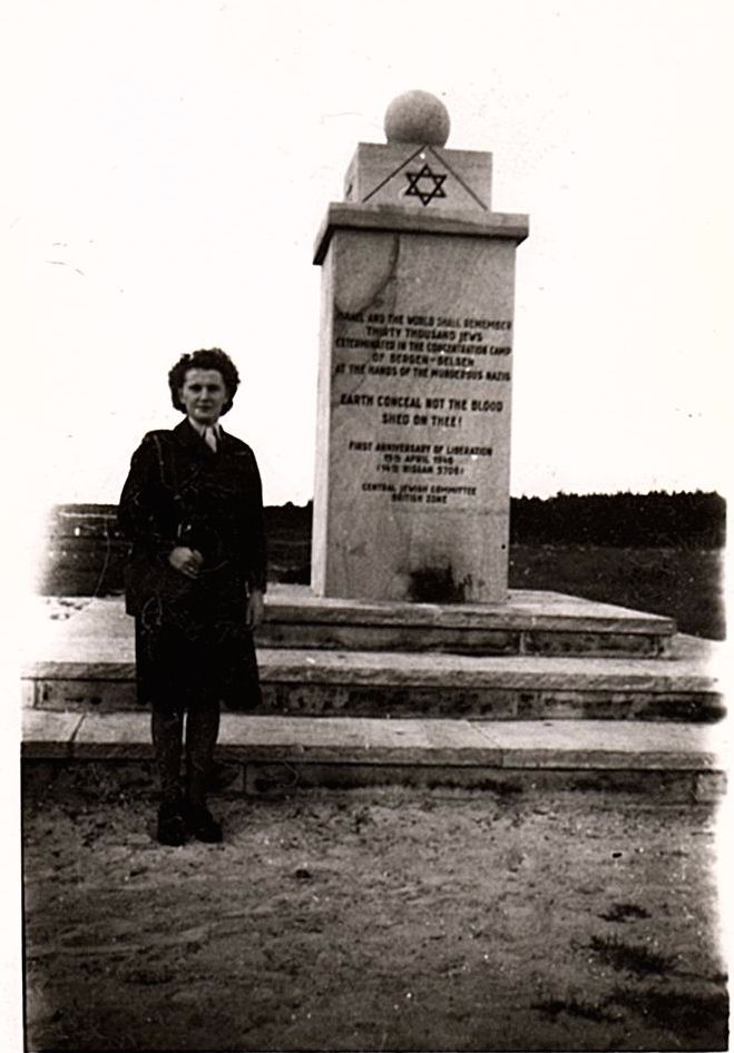 A Canadian nurse stands beside a memorial at Bergen Belsen, a Nazi concentration camp in Saxony, Germany, ca.1946.