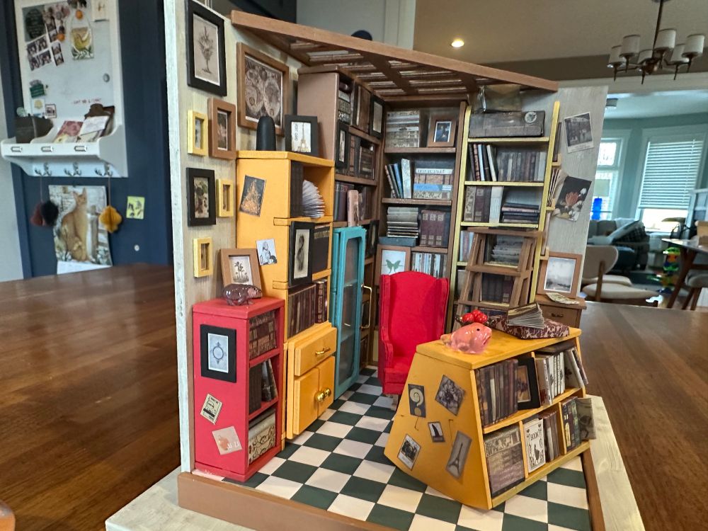 A close view of the model office. It is very busy. There are many small objects and shelves. 