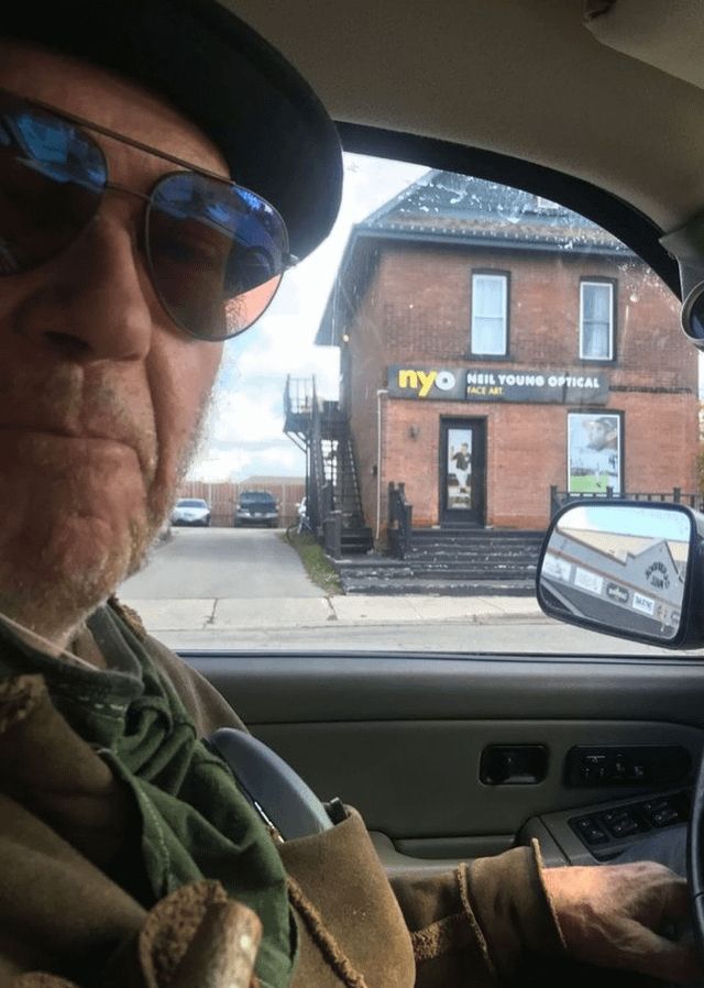 Neil Youn poses in front of a building labelled “Neil Young Optical.”