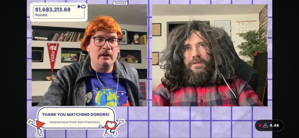 Screenshot of P4A2025 of John green and Craig benzine wearing wigs. John had a short bright orange do. Craig has a long dark and grey curly but messy wig. 