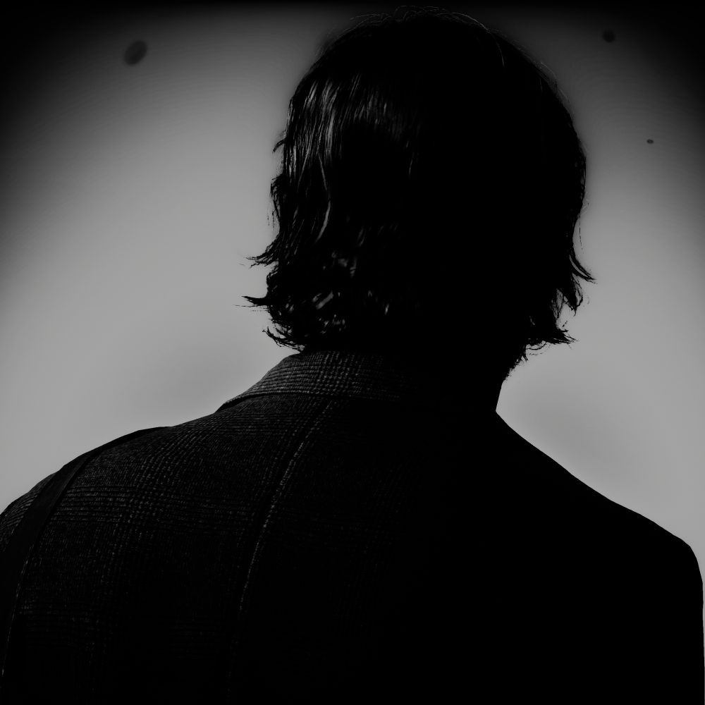 Virtual photography capture from Alan Wake 2. Alan Wake is viewed from behind, only his shoulders and head are visible, in a stark grayscale image. Alan and his blazer are dark against a foggy grey background.