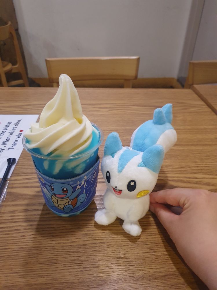소다맛 슬러시 위 소프트 아이스크림이 담긴 컵과 파치리스 인형을 잡고 있는 손