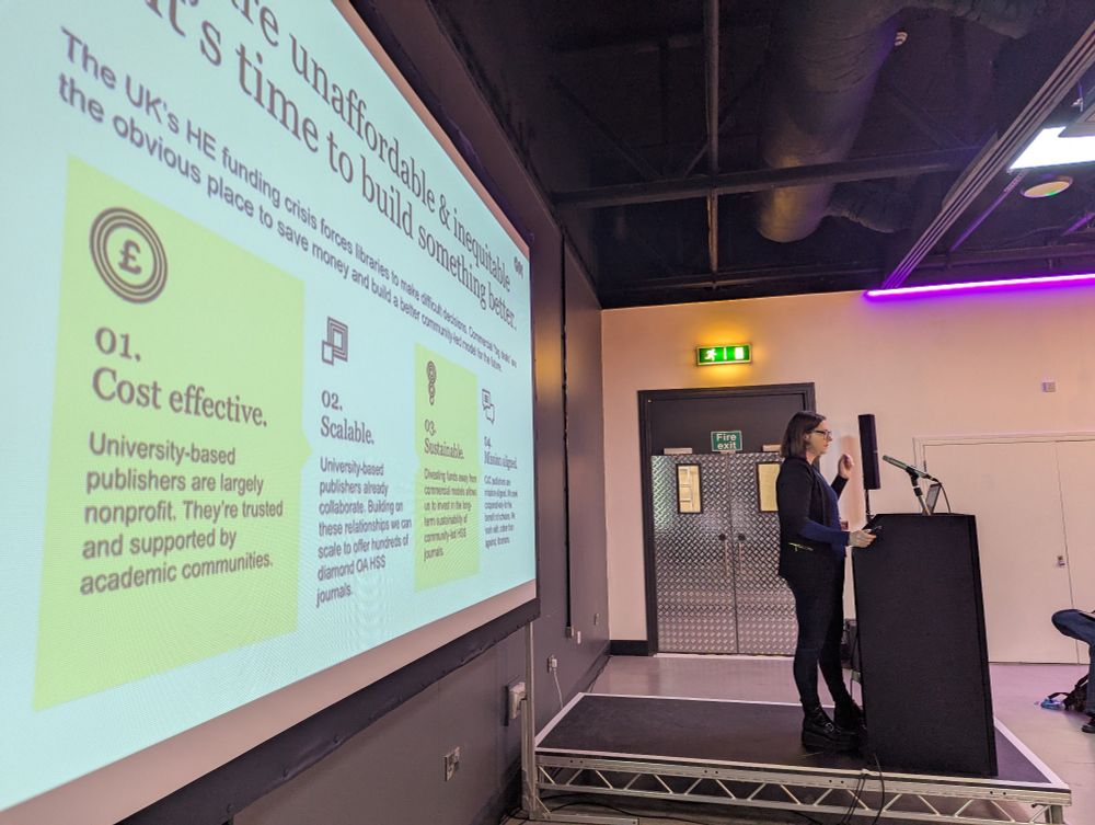 Speaker at podium alongside slide with key terms including cost effective and scalable 