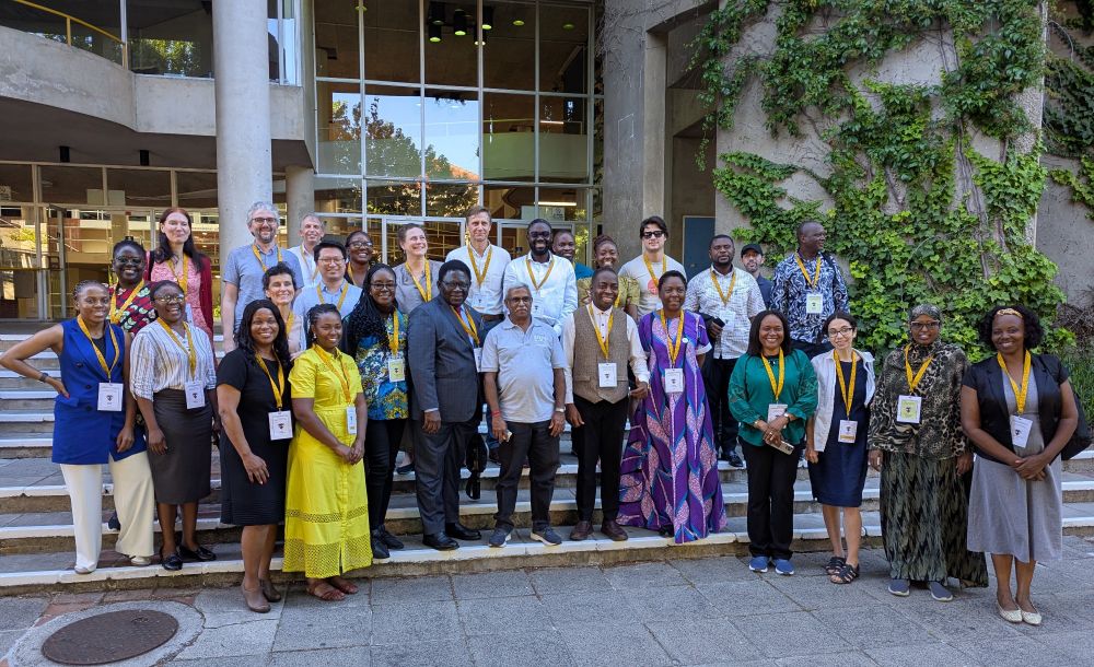 Around 25 workshop participants standing on some steps smiling at the camera