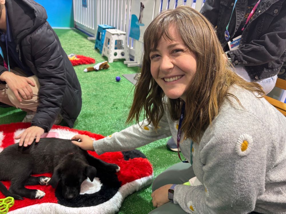 Dr Briley Lewis petting a sleeping, black puppy