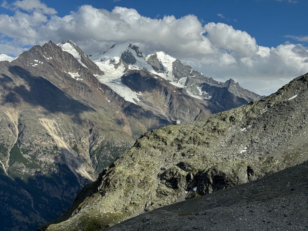 Mountains with snow and a cabin in the distance on a ridge 