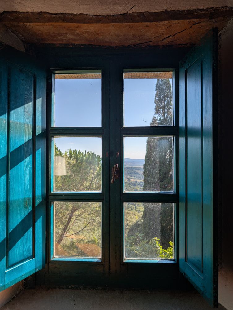 View through a window with vast fields and hills in the background