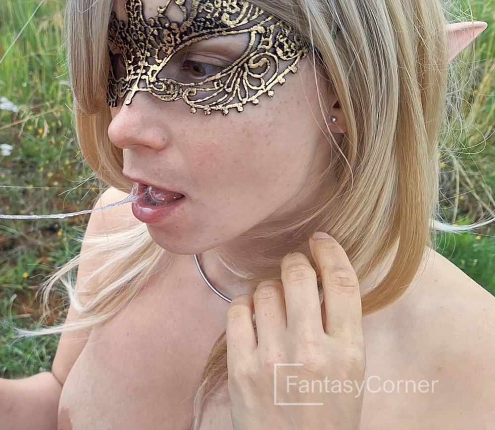 A naked blonde elf is examining something closely and spittle is stretching from her mouth to something outside the picture.