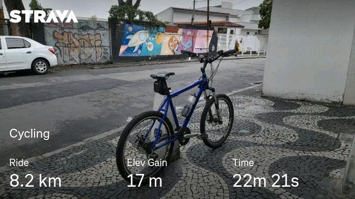 Hardtail mountain bike on sidewalk with wave pattern made from small tiles. Road and colorful mural in background.