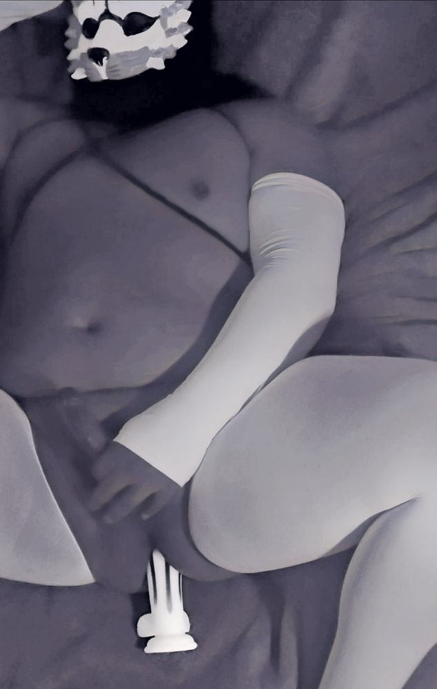 The Indulgent Chimera stroking their cock in suspender hose and harness with dildo inserted. 