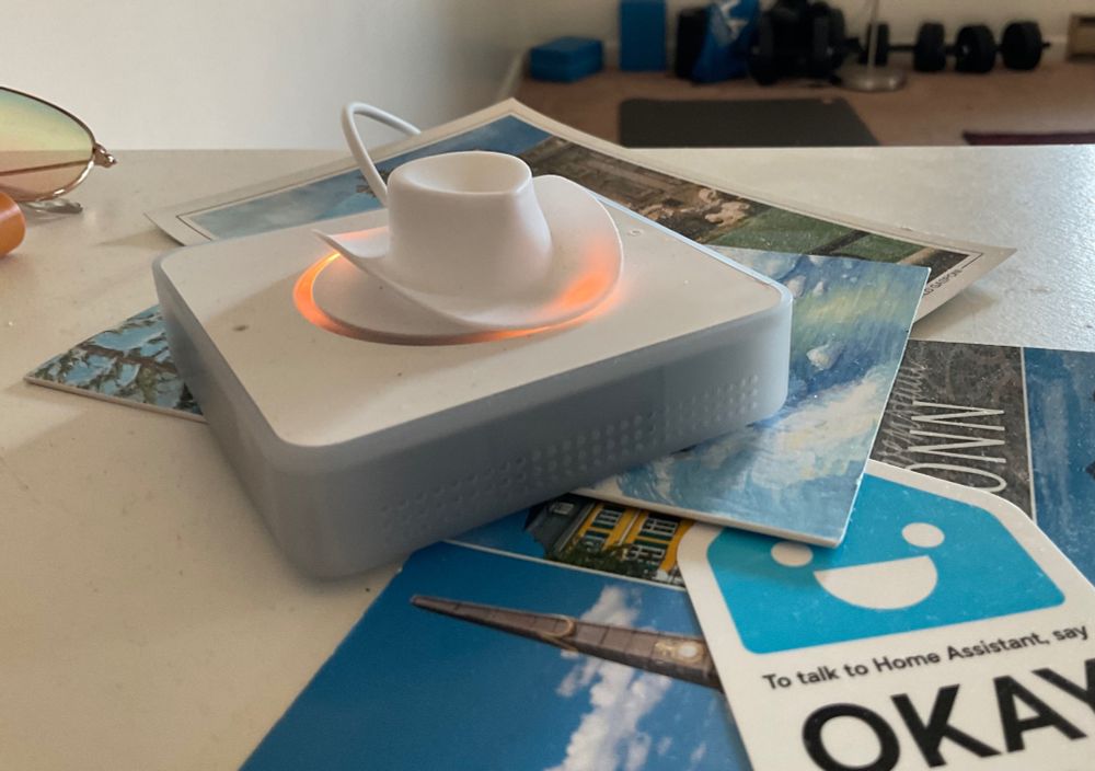 A rectangular device with an orange LED circle with a little white plastic cowboy hat on top.