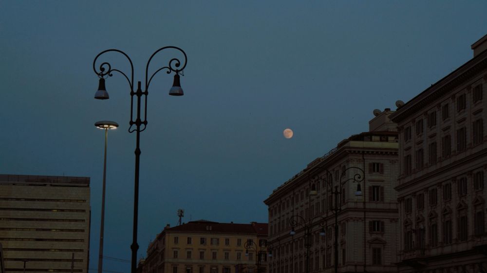 building at night with a visible moon and street lights in rome, italy