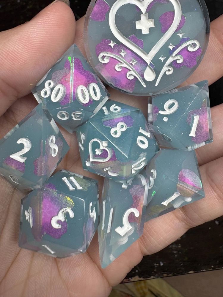 Light blue dice set with holographic shimmer and pink iridescent flower and petal stickers. Numbers inked in white. 
