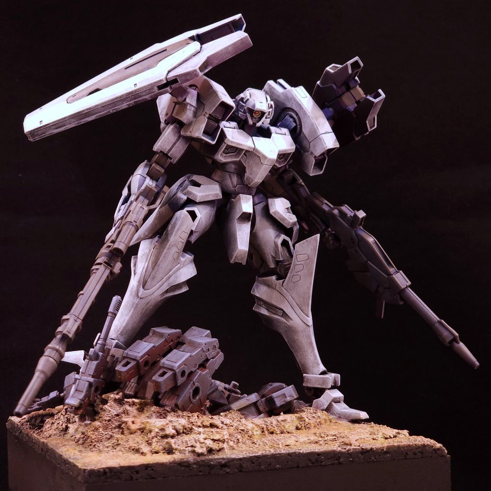 Image of a painted plastic model of an Armored-core inspired mech. The mech is brandishing a weapon in each hand and standing on a defeated machine.