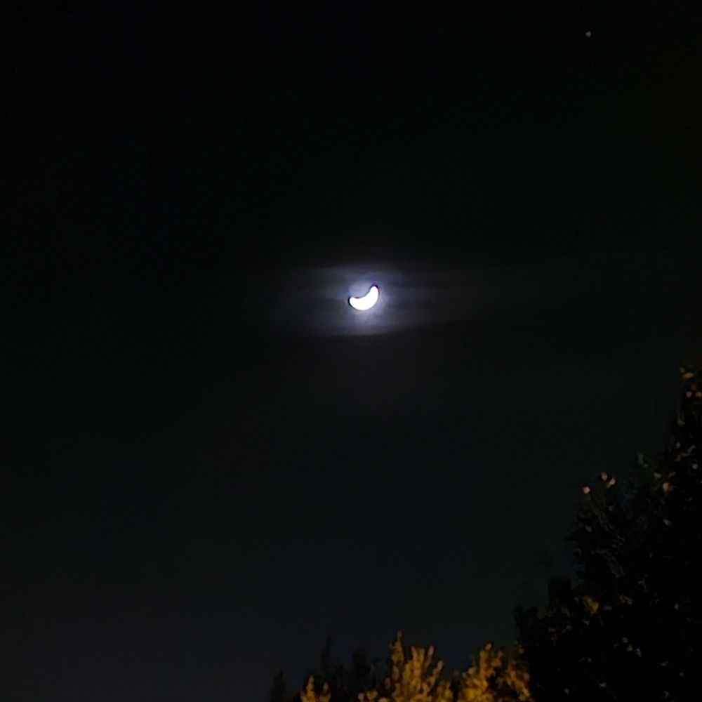 Blurry dark night sky, with a teeny tiny crescent moon visible