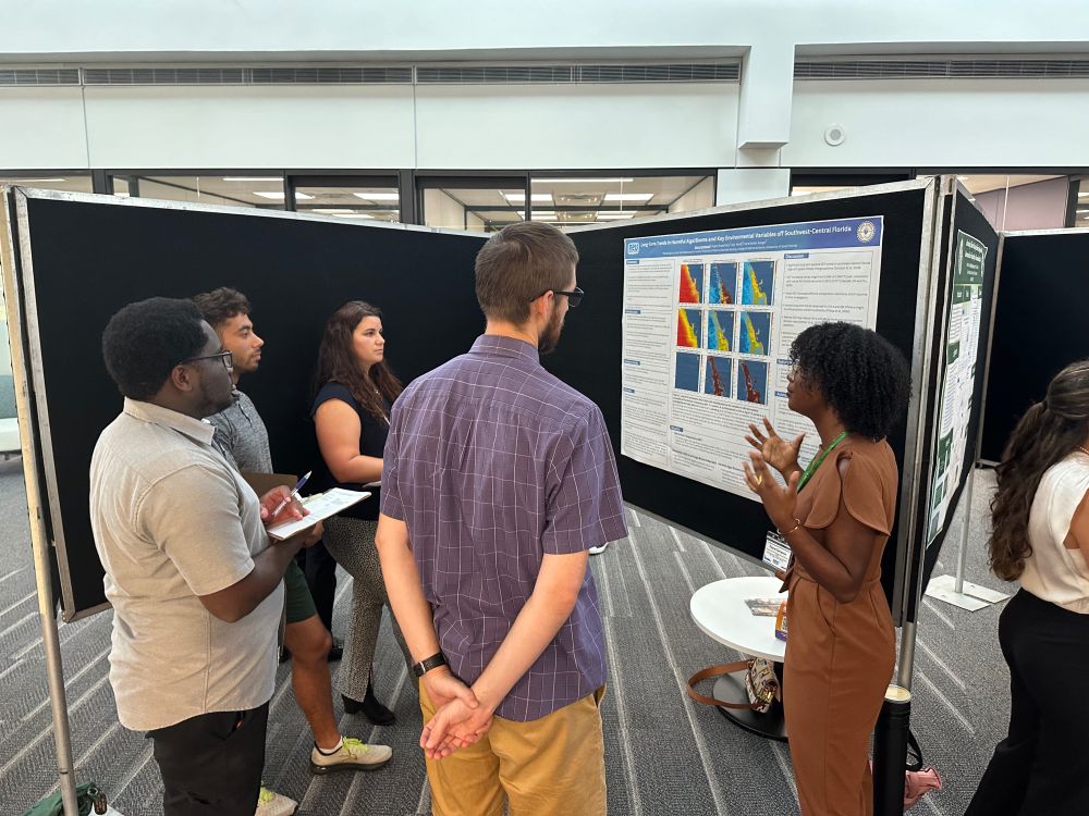 A group of students listening to a poster presentation