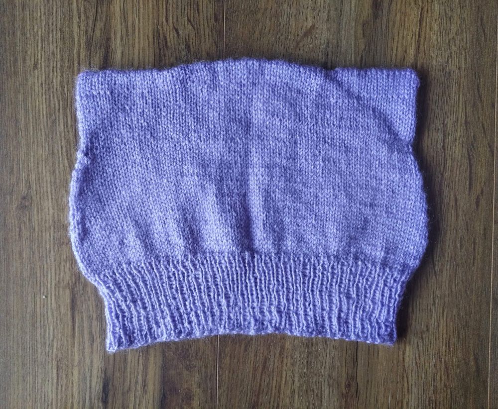 Knitted beanie with hat ears in lilac lavender purple on a wooden brown background