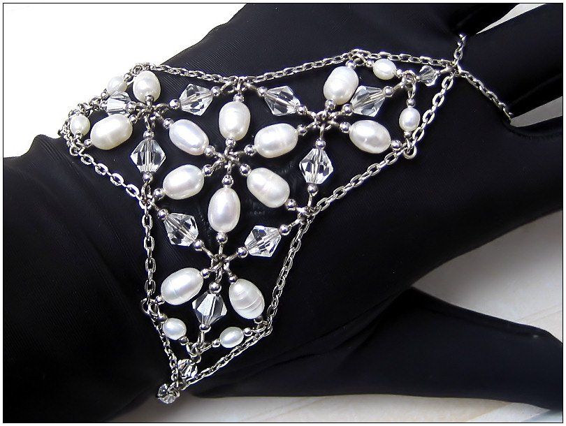 Pearl, crystal and silver palm bracelet on black glove background