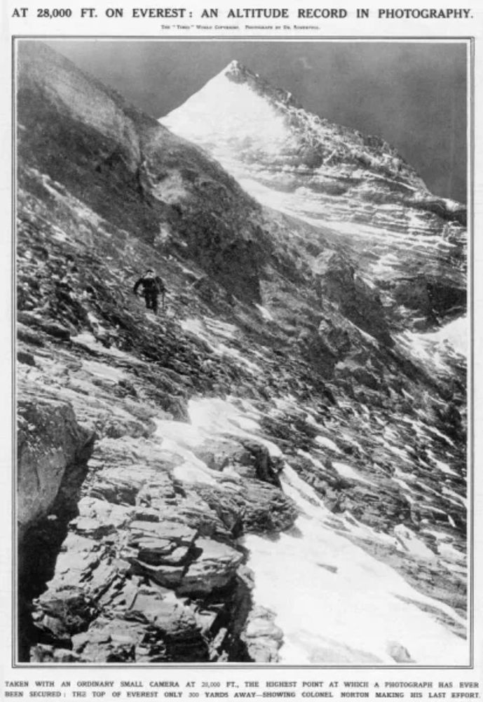 Black and white photograph of the rocky and steep upper North Face of Mount Everest showing mountaineer Edward Norton carefully traversing the slope in the middle ground, with the snowy summit in the background. Photo taken on the 1924 Everest expedition by Howard Somervell. 