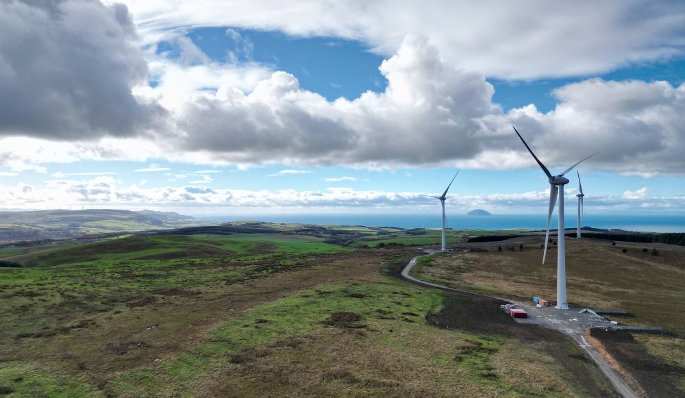 View of Kirk Hill wind farm near Turnberry in Scotland, with Ailsa Craig island visible in the distance.