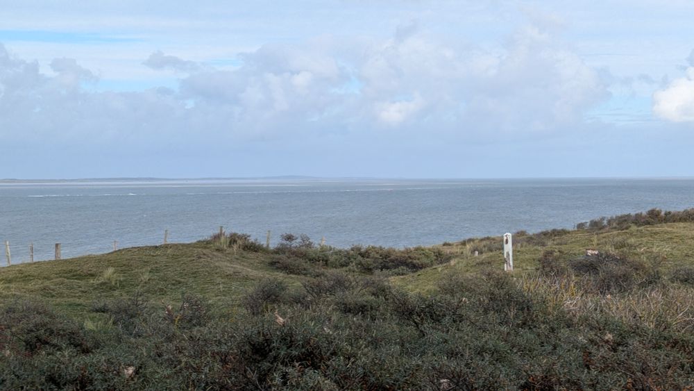 Noordelijkste punt van Texel vanaf de vuurtorenduin. Op de voorgrond groeit duindoorn. Aan de horizon zie je Vlieland