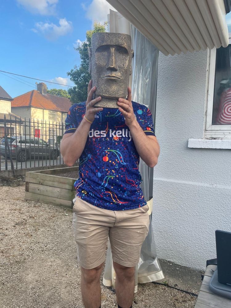 A man with an Easter Island head in front of his face. 