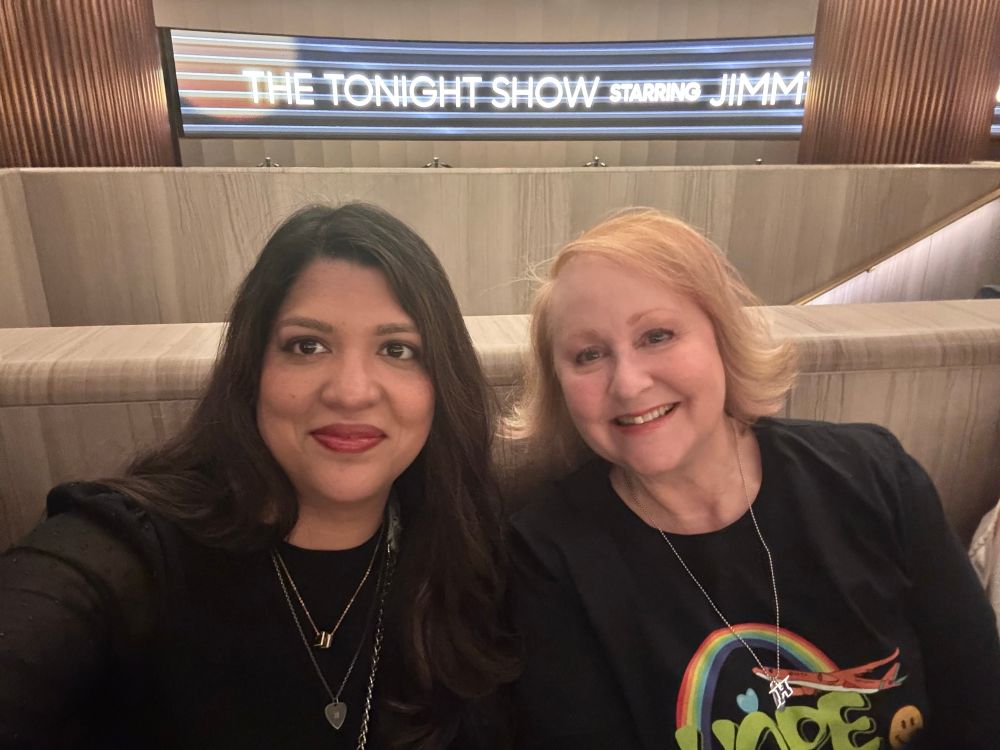 Two women in black, smiling at the camera with a sign behind them that reads “The Tonight Show starring Jimmy Fallon.”