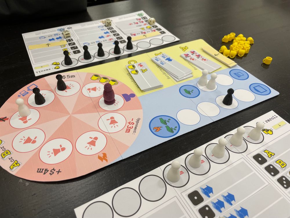 A photo of my game Dot Com. In the center of the table is a game board, with player pawns and cards on top of it. Each player also has their own personal board showing the actions they can take. Not pictured is the companion app for the game that keeps track of your money!