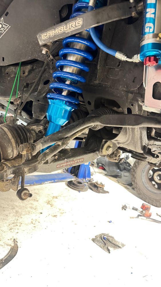 The lower bearing end of a King 2.5 Coilover Shock, bolted into a Cambur lower control arm with the Spindle removed. On the right is the remote reservoir with adjuster for the High/Low Speed Compression