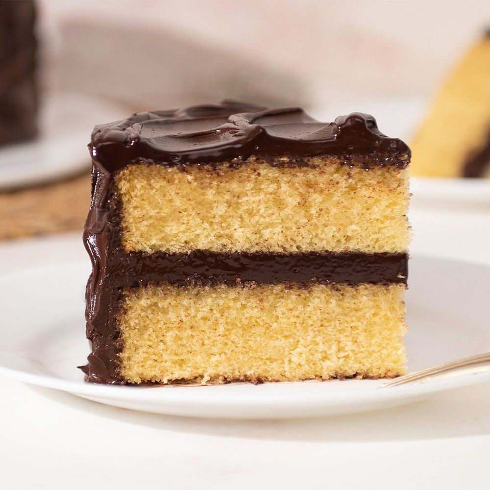 Image of layered cake that’s yellow with chocolate icing. 
