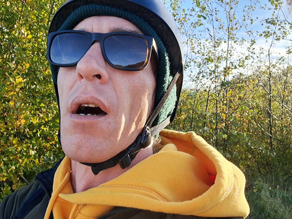 Me (my head and shoulders only) wearing a yellow hoodie, sunglasses and a cycling helmet. My head is tilted slightly backwards because of my sight; sunglasses have reading-field. For some reason my mouth is open though I am not speaking or about to.
I had forgotten to turn the camera away from selfir-mode! 