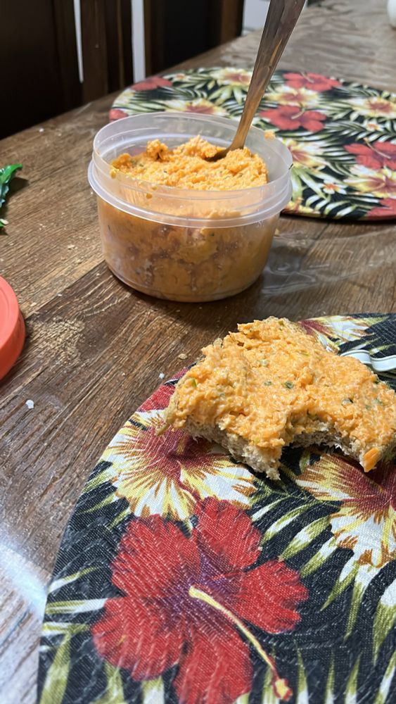 Imagem de uma fatia de pão com patê de cenoura já mordido e um pote contendo mais patê 