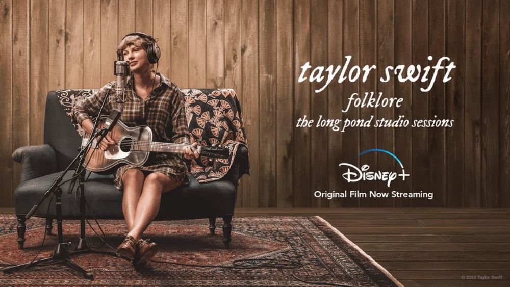 Taylor Swift sits on a tiny couch with a plaid dress on playing guitar. The ad states “taylor swift folklore the long pond studio sessions.” 