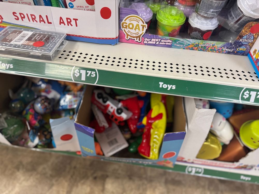 A shelf label indicating toys cost $1.75. Other toys and displays show the red sticker covering the original price of $1.25.