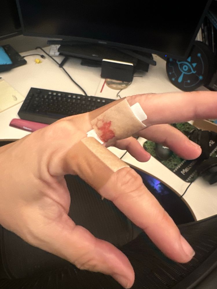 Initial unbandaging of a middle finger boo-boo. The bandaid is about 30% saturates with blood.  