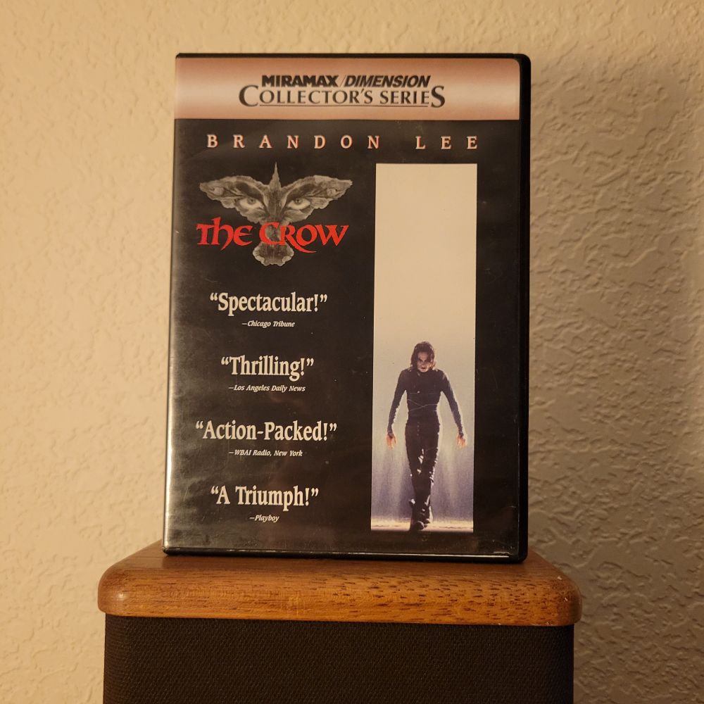 A deluxe version of "The Crow" on dvd. It's displayed on a small brown speaker. In front of a tan wall.