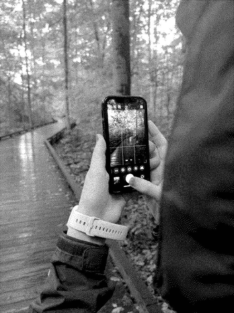 black and white dithered photo of a person pressing the shutter button in the iOS camera app