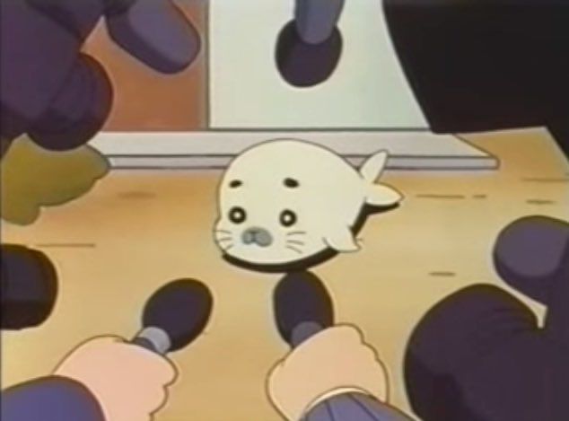 anime seal surrounded by many microphones 