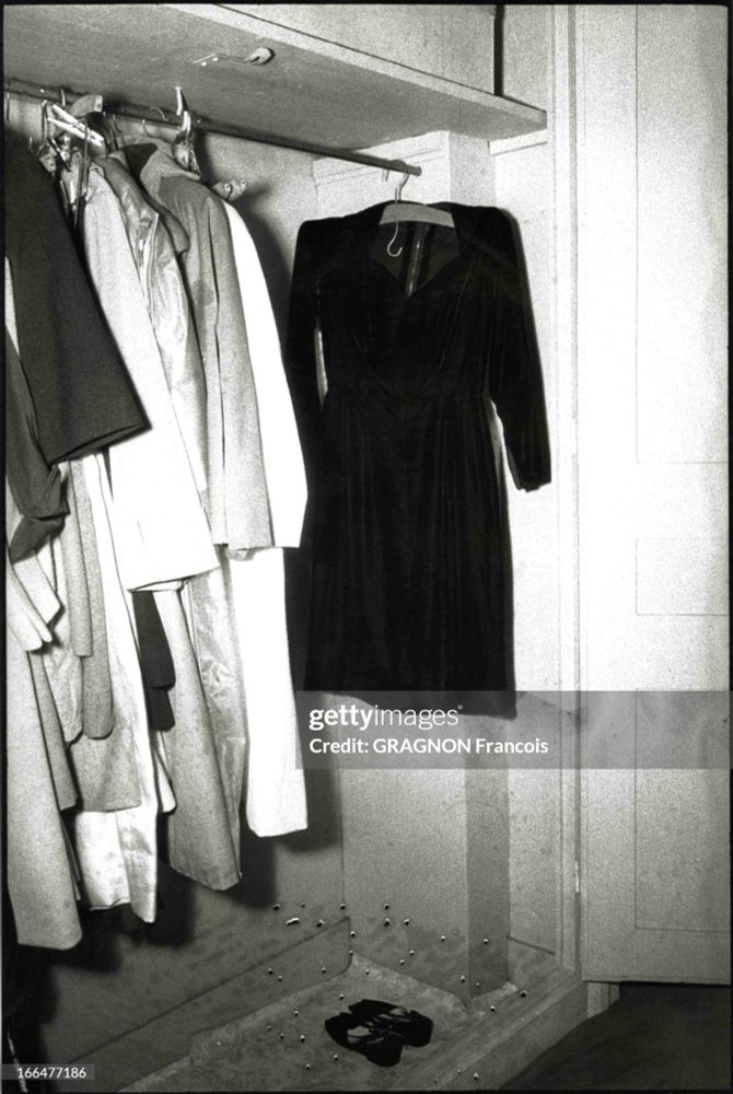 A 1960s photo of a woman's wardrobe. A handful of dresses hang on a rail. 