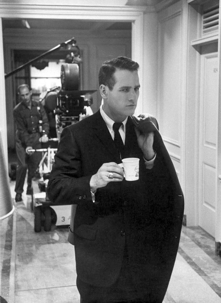 Paul Newman wearing a dark sack suit with a white button-down collar shirt. His tie is worn with a four-in-hand knot. 
