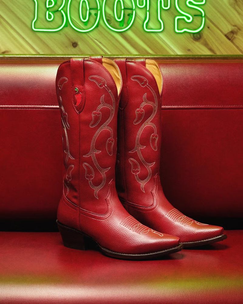 Product shot of the red cowboy boots. There are chili peppers on the boot's tops (shaft)
