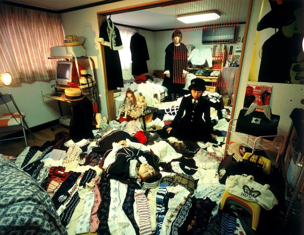 Three people in a room full of clothes. 
