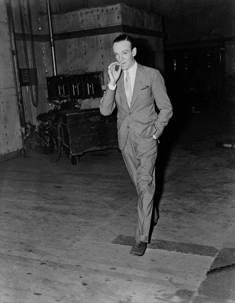 Fred Astaire wearing a suit, white shirt, and suede shoes. His tie is worn with a four-in-hand knot. 