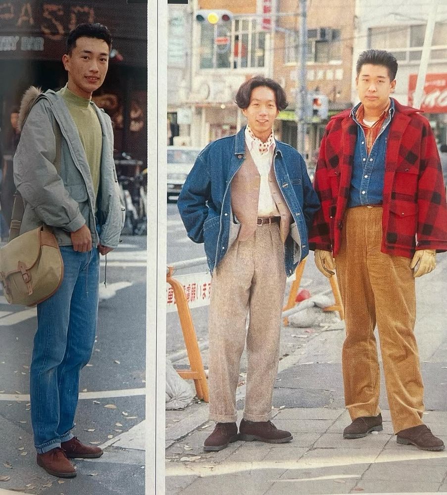 A man wearing a light blue windbreaker jacket with light blue jeans. Then a man wearing a denim chore coat with brown pleated trousers. And another man wearing a red checked jacket with blue denim shirt and golden brown trousers. 