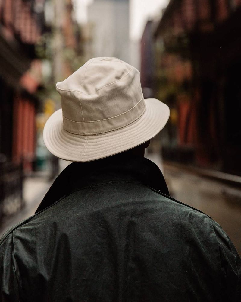 A man in a green coat and a tan bucket hat. 