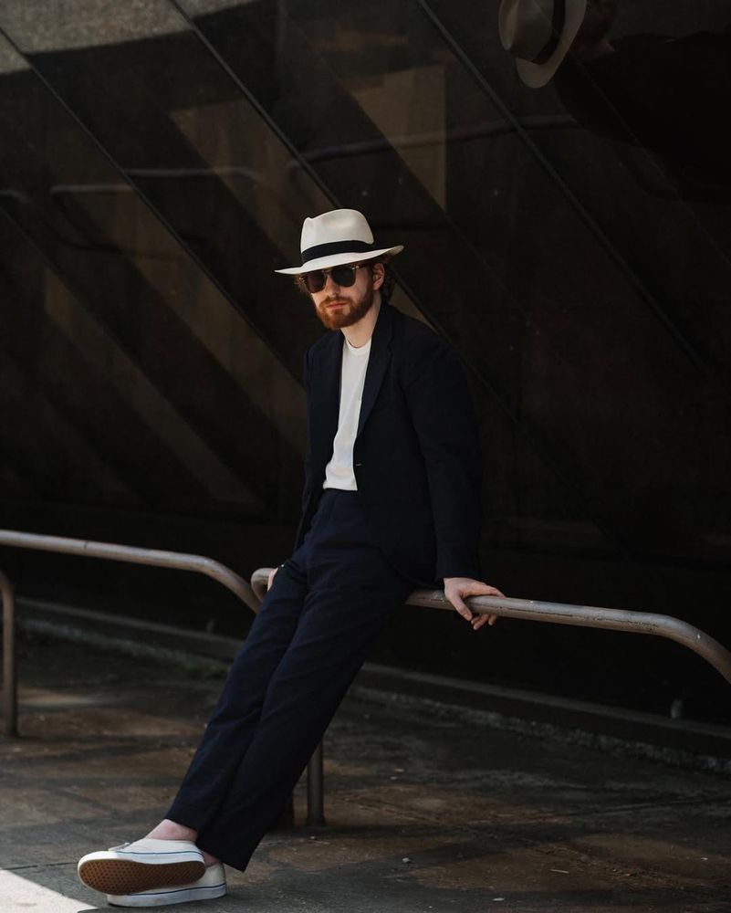 A man in a navy seersucker suit, white t-shirt, and a Panama hat. 