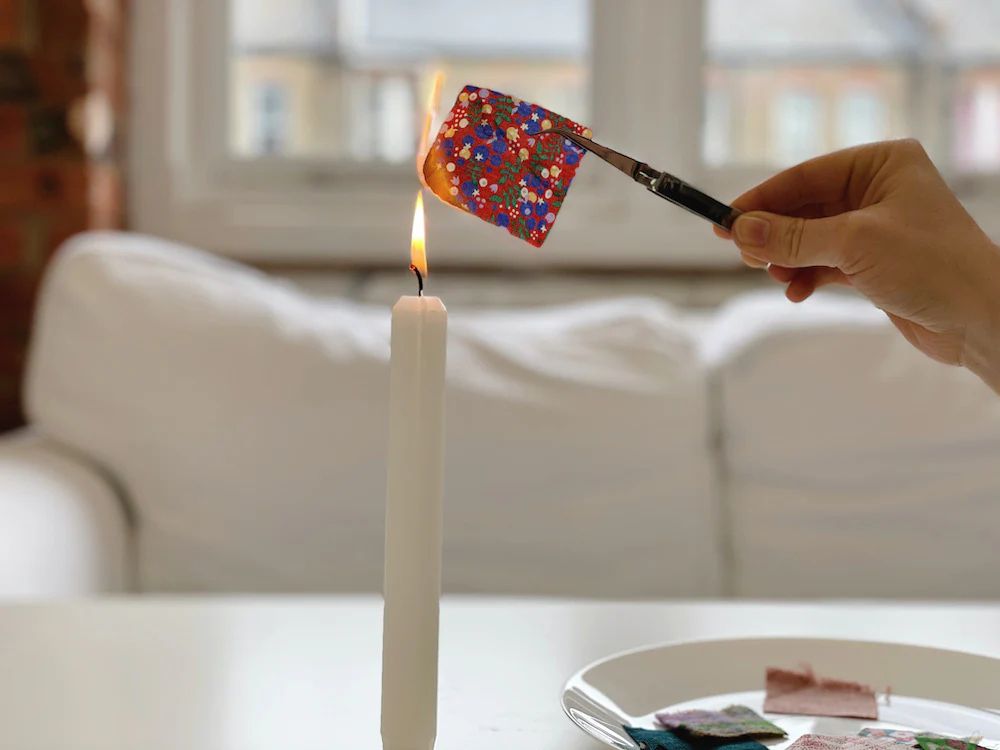 Someone burning a swatch using a candle flame. 