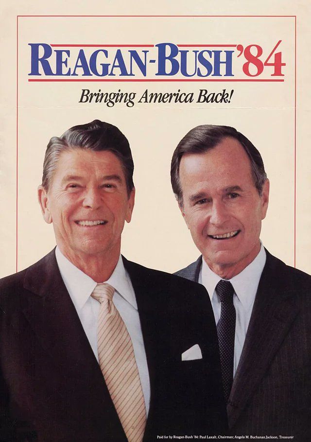 Reagan with George HW Bush. Both men are wearing dark suits and white dress shirts. Reagan has a yellow tie with a Windsor knot; Bush has a dark grey or navy tie with a four-in-hand knot. 