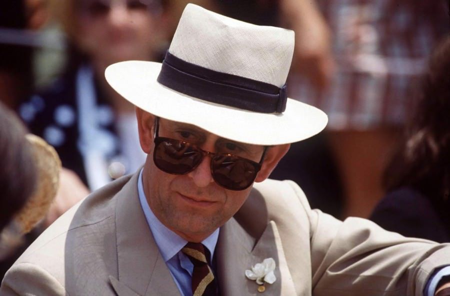 King Charles in a Panama hat and a tan double-breasted suit. 